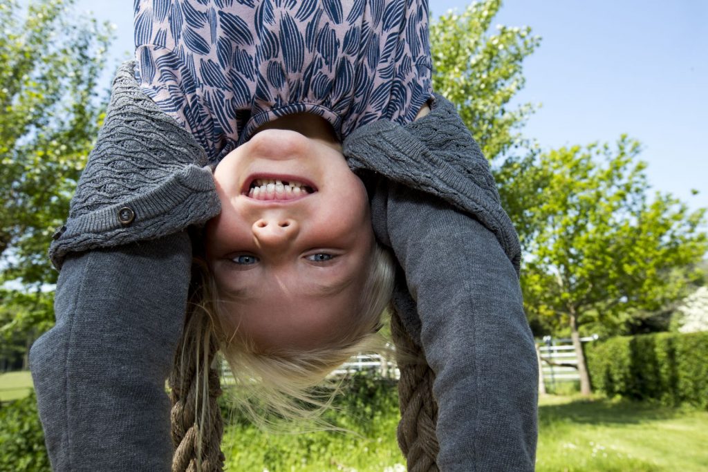 Girls hanging on their heads from climbing frame