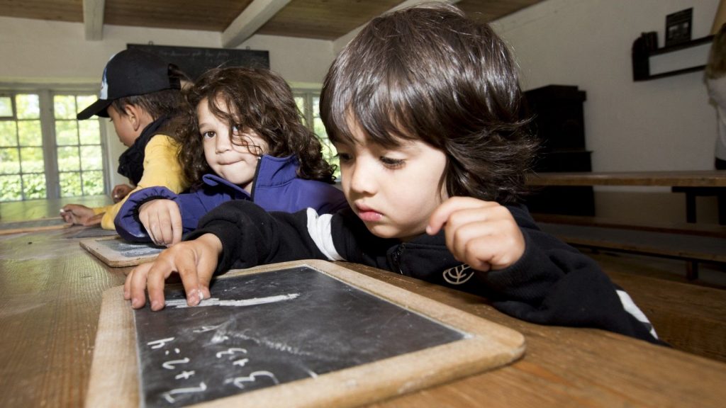 Tre små børn, der skriver på tavlerne i Reventlow-skolen