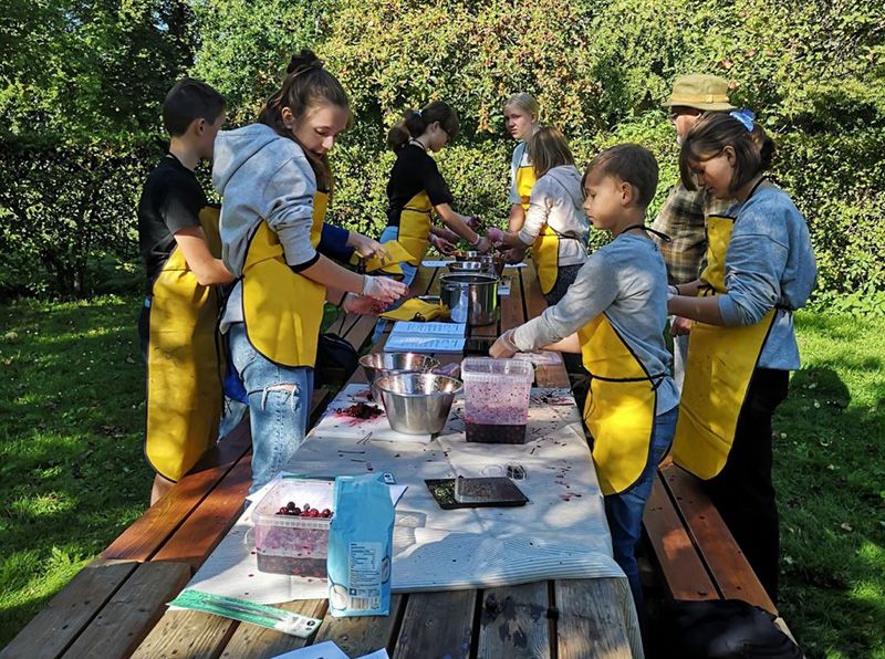 Children at long tables at the open-air museum work with fruit