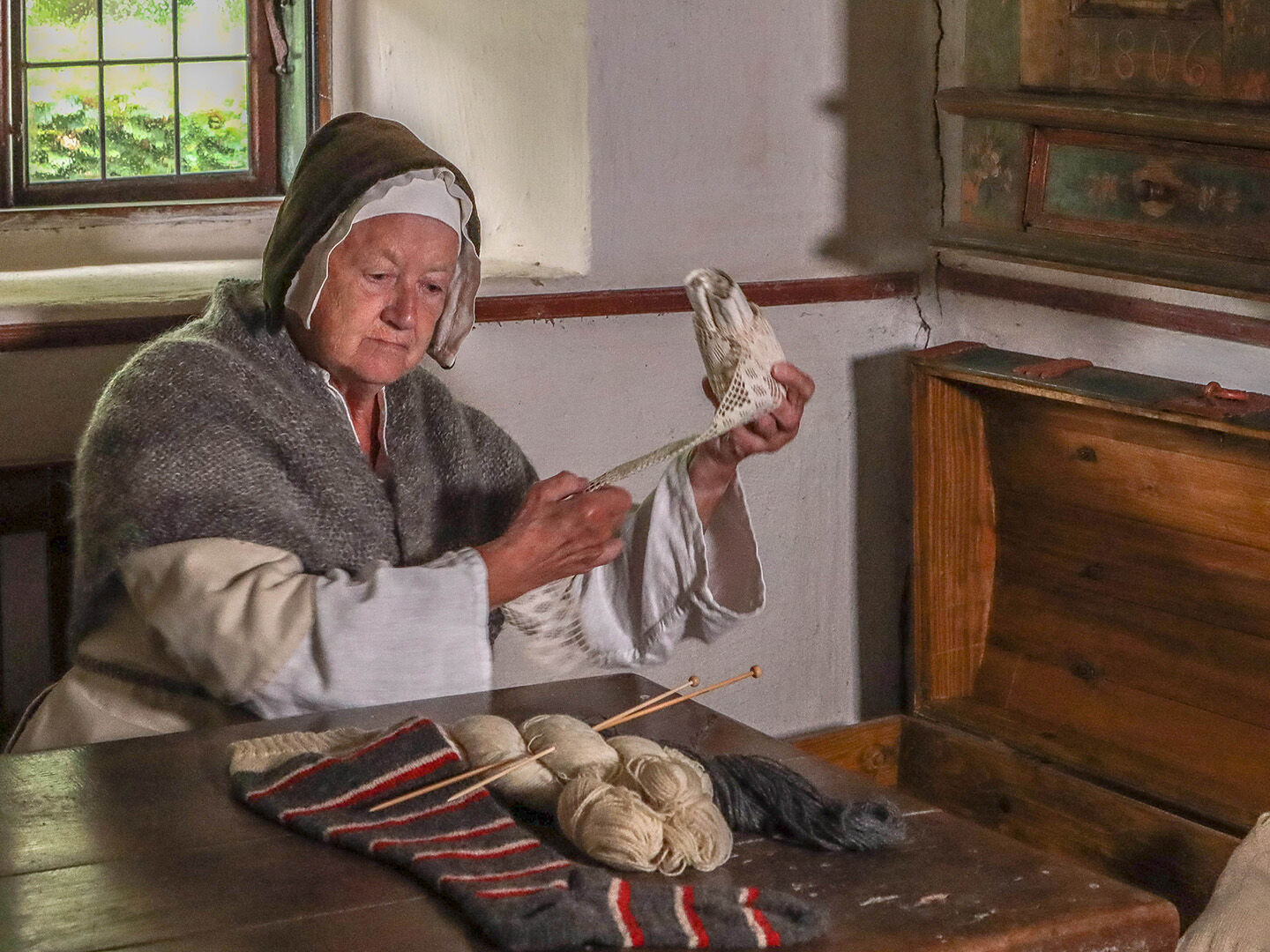 One of the museum's volunteers wearing an old costume sits by the knitting in one of the old houses at the open-air museum.