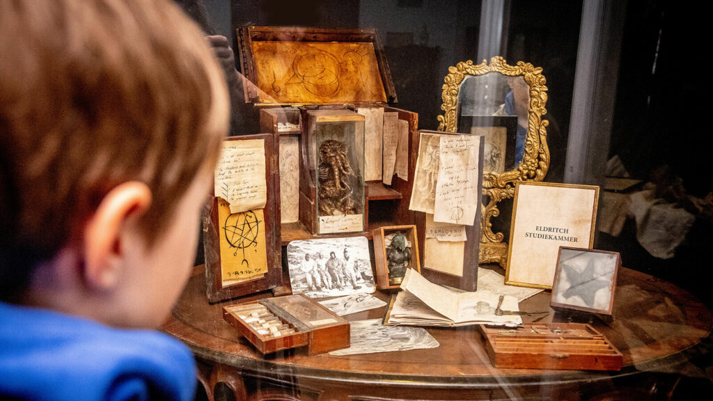 Child looking at a collection of objects on a table in the Museum Obscurum