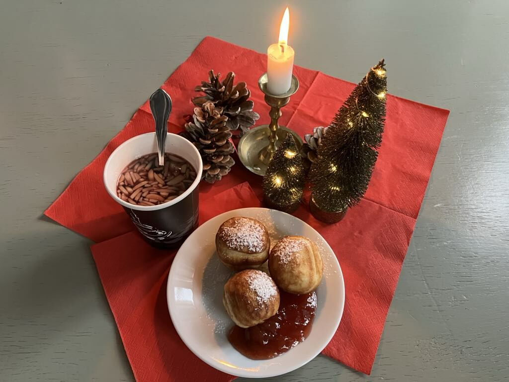 Anretning med gløgg og æbleskiver, stearinlys, kogler og anden julepynt