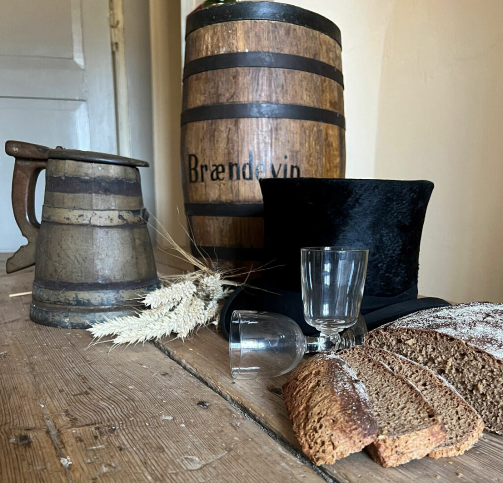 Brot, Bier und Schnaps auf einem Holztisch in einem der alten Häuser im Freilichtmuseum von Maribo